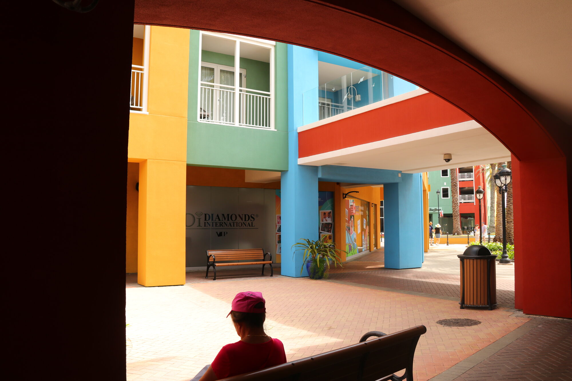 Colorful courtyard seen through an arch, person resting on a bench