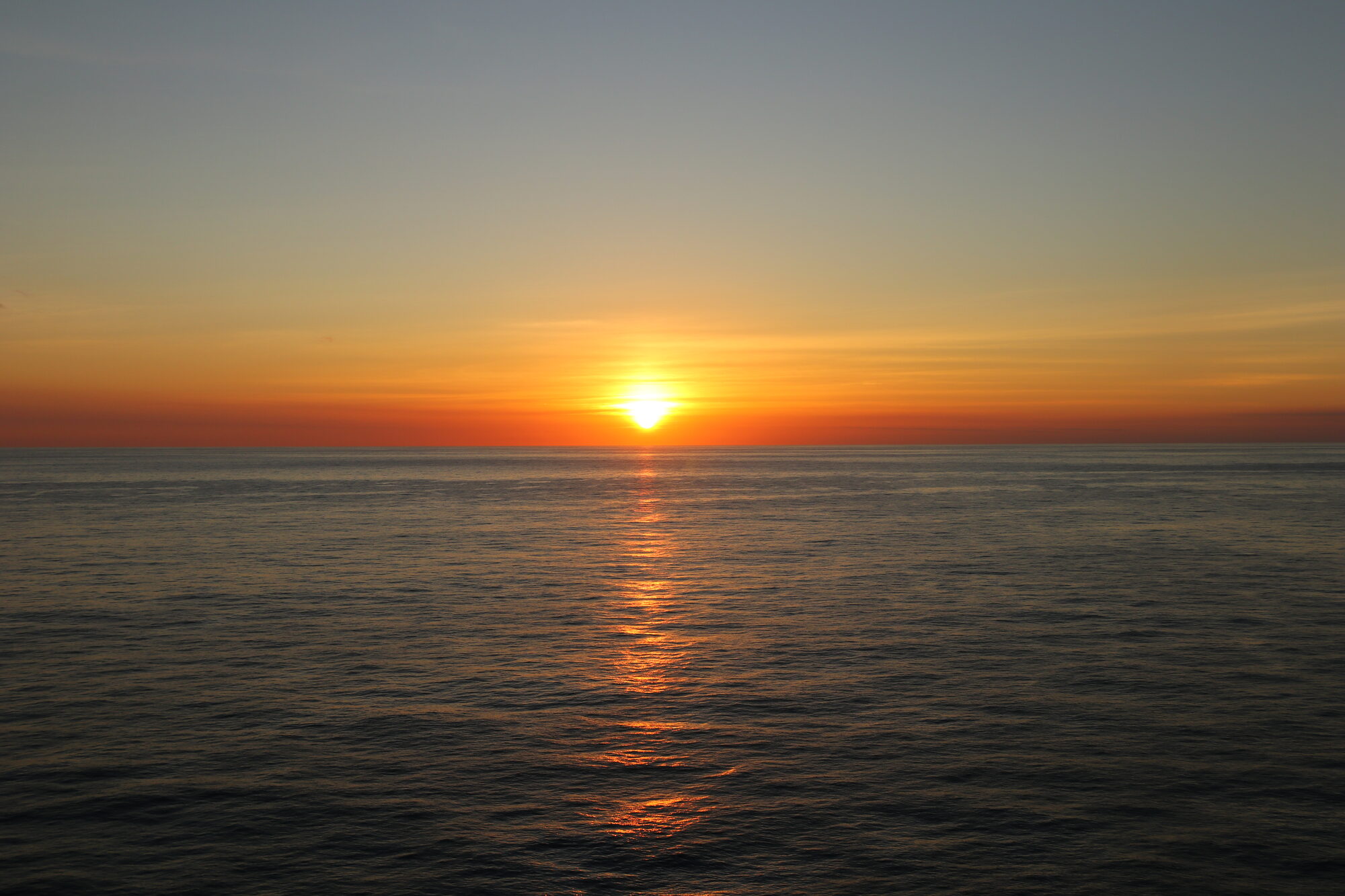 The sun setting over the open sea horizon