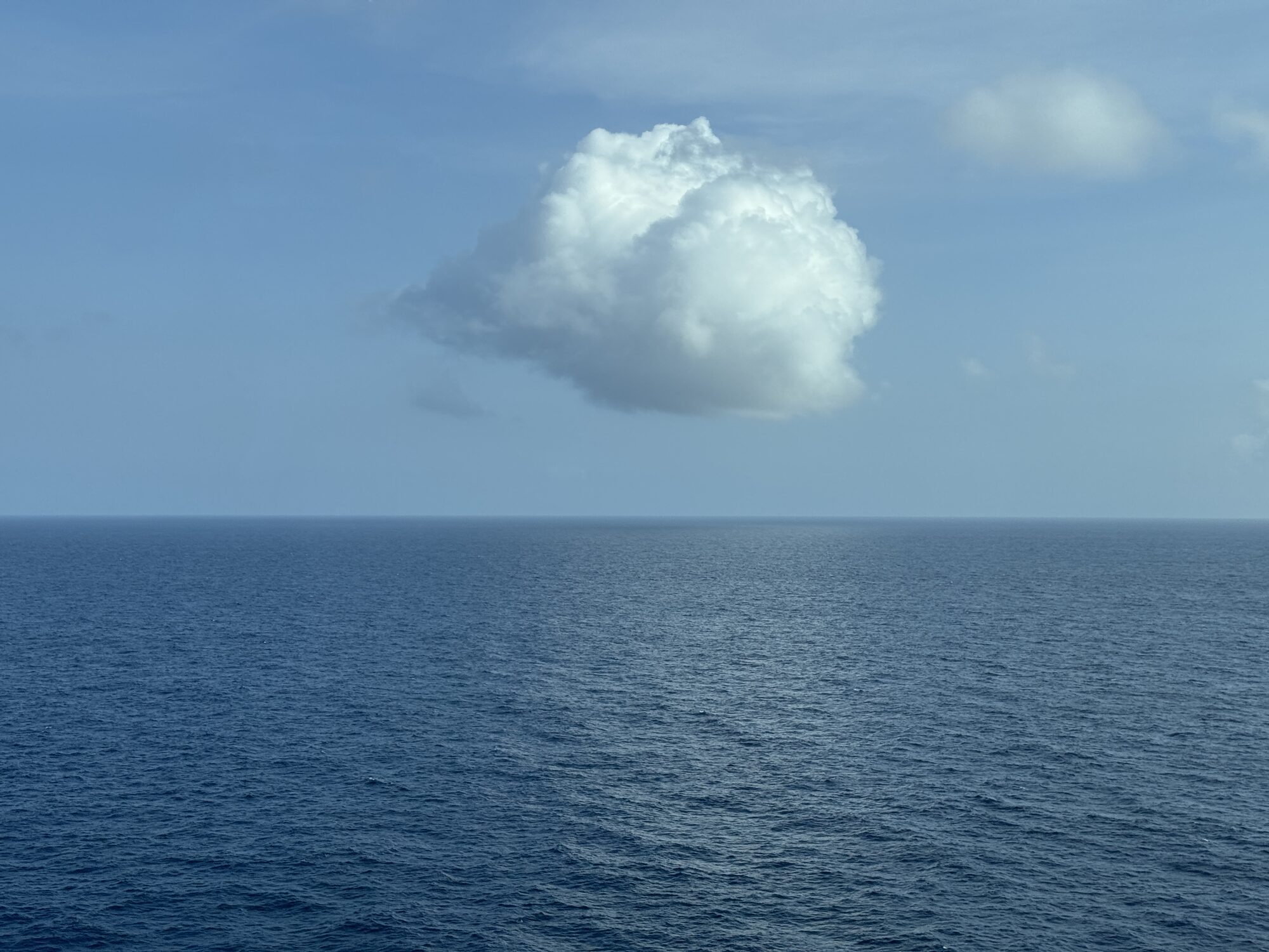 A single cumulus cloud over the open blue sea