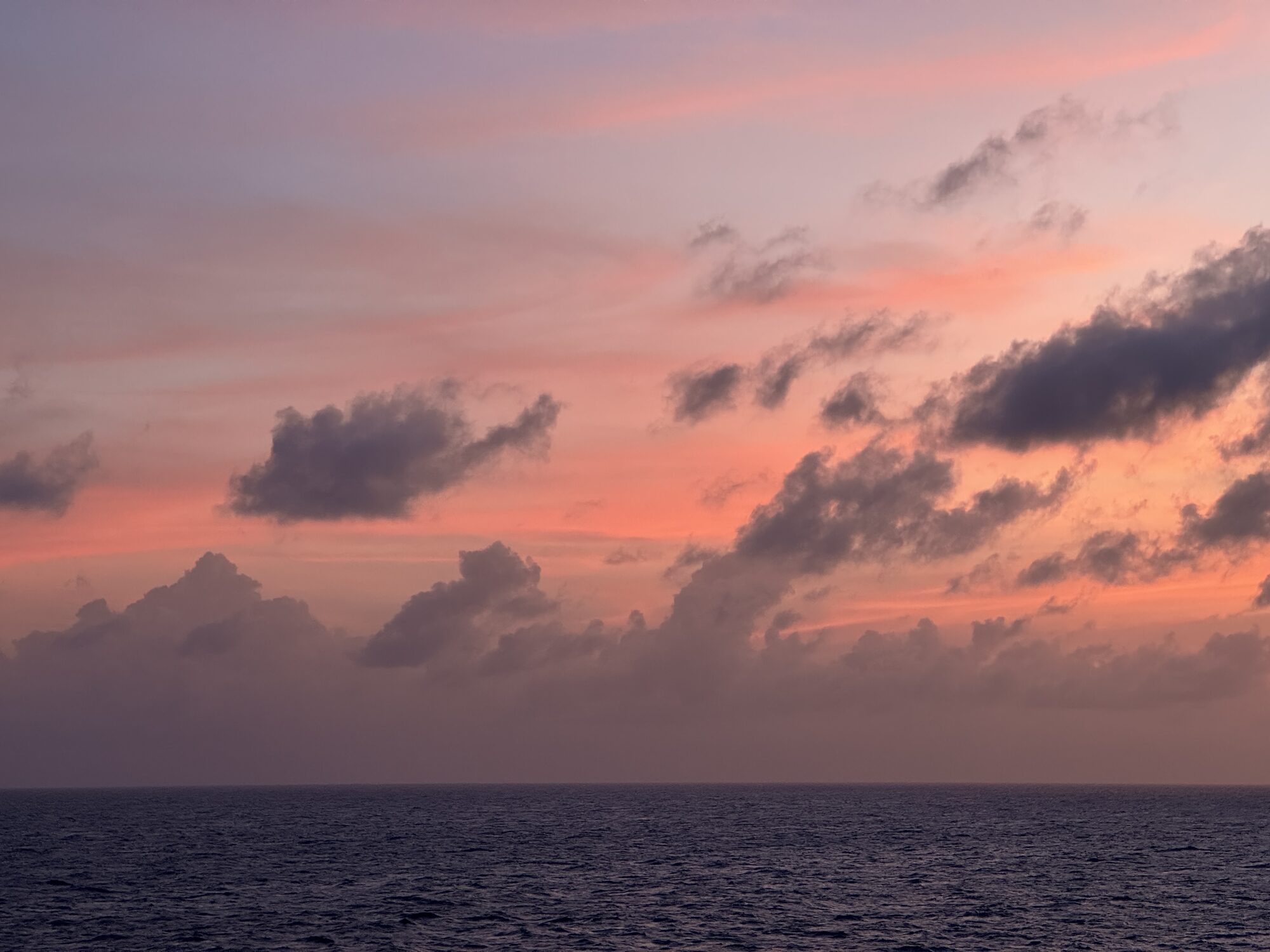 Pink and lavender clouds over the darkening sea