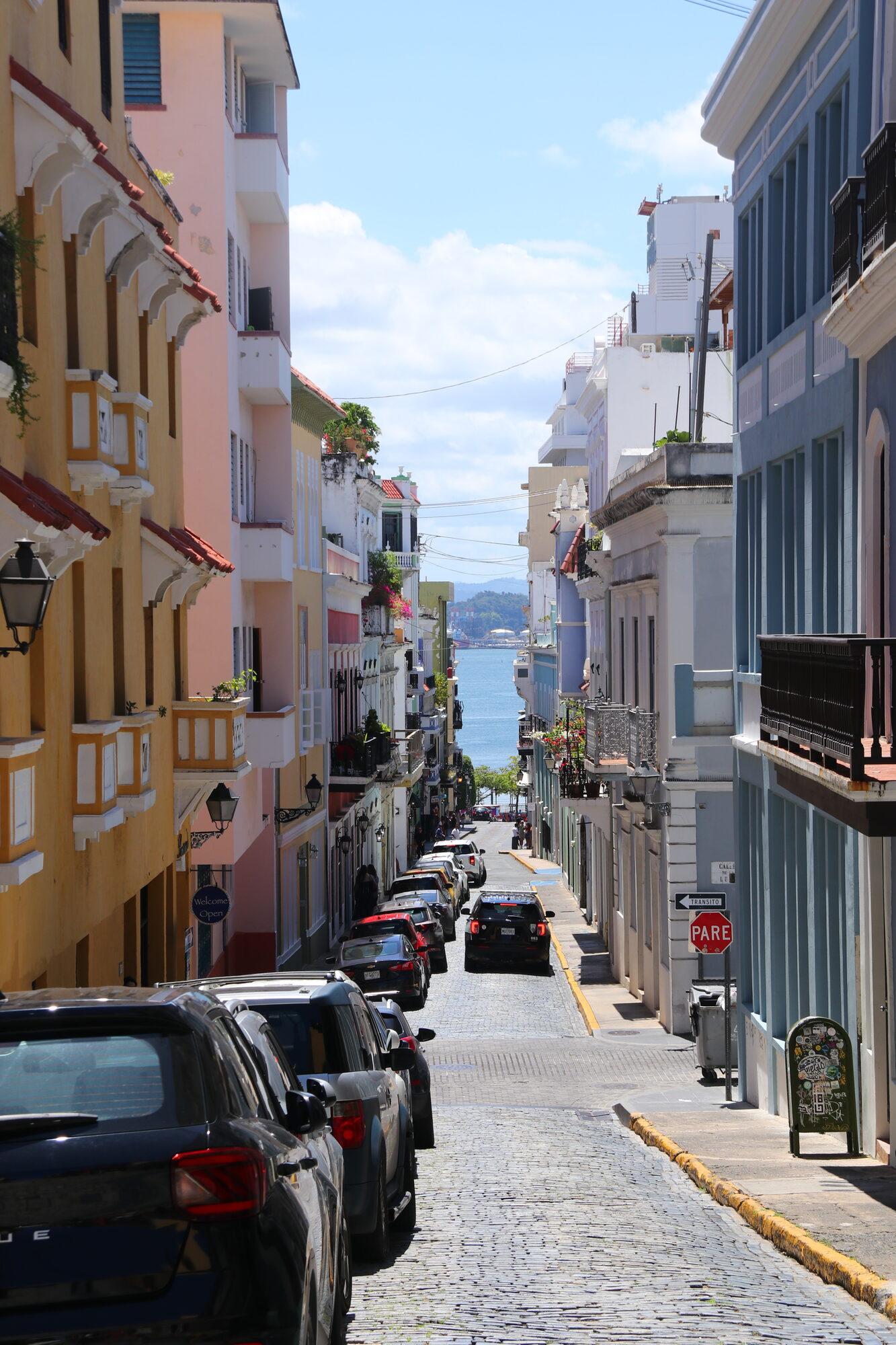 Narrow old-town street with pastel buildings sloping down to the sea