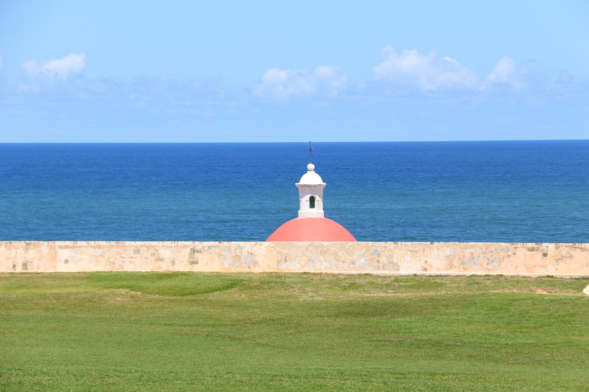 Red-domed chapel behind the fortress wall against the sea