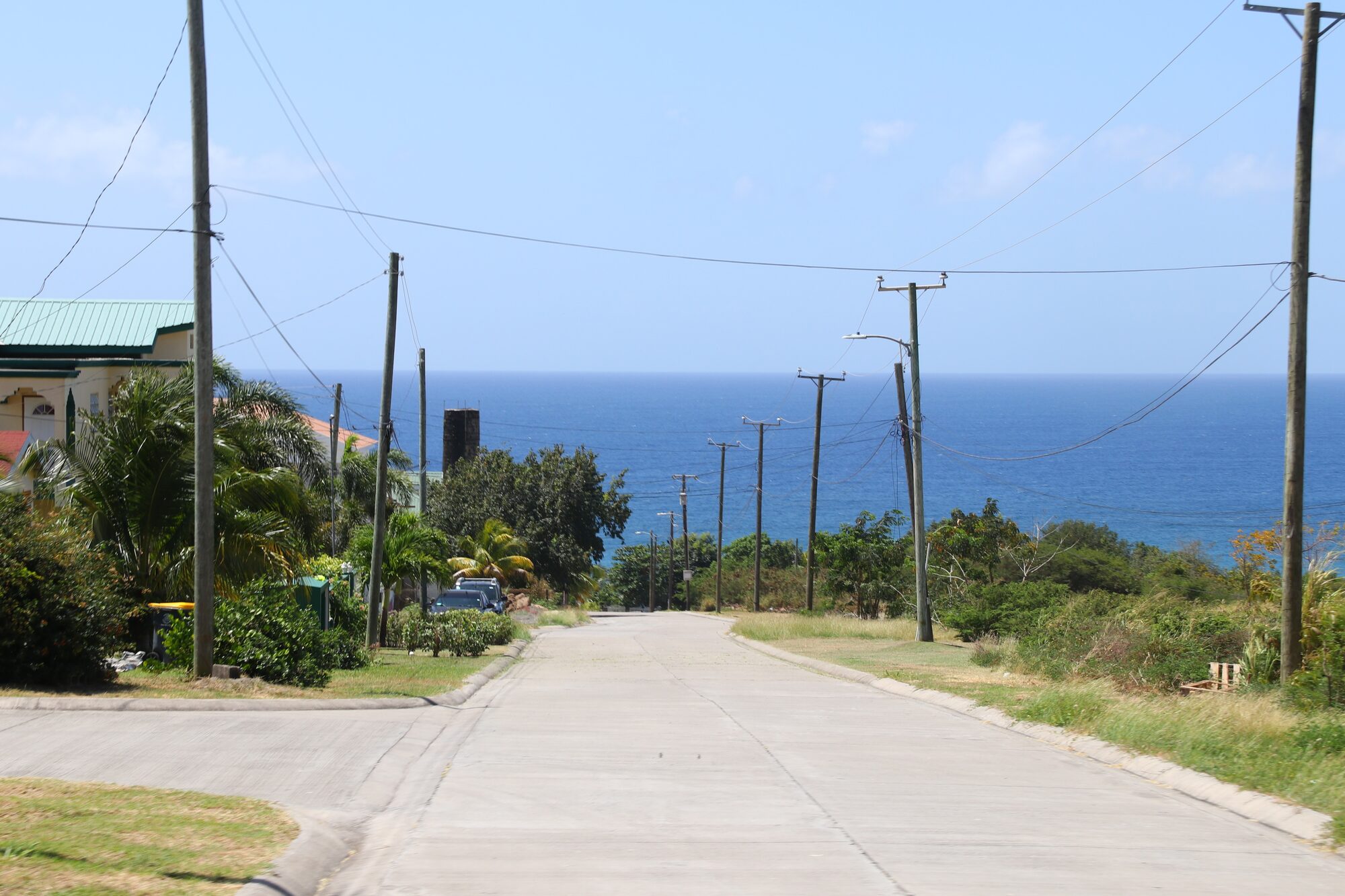 A road sloping down toward the sea between power poles