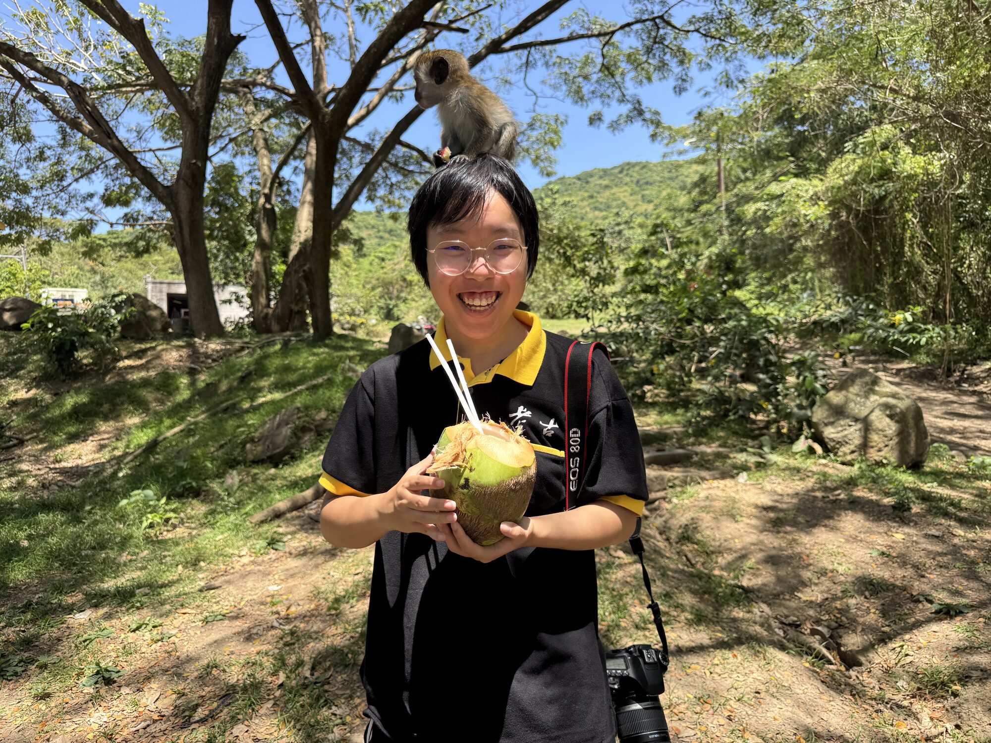 Holding a coconut with a green vervet monkey perched overhead
