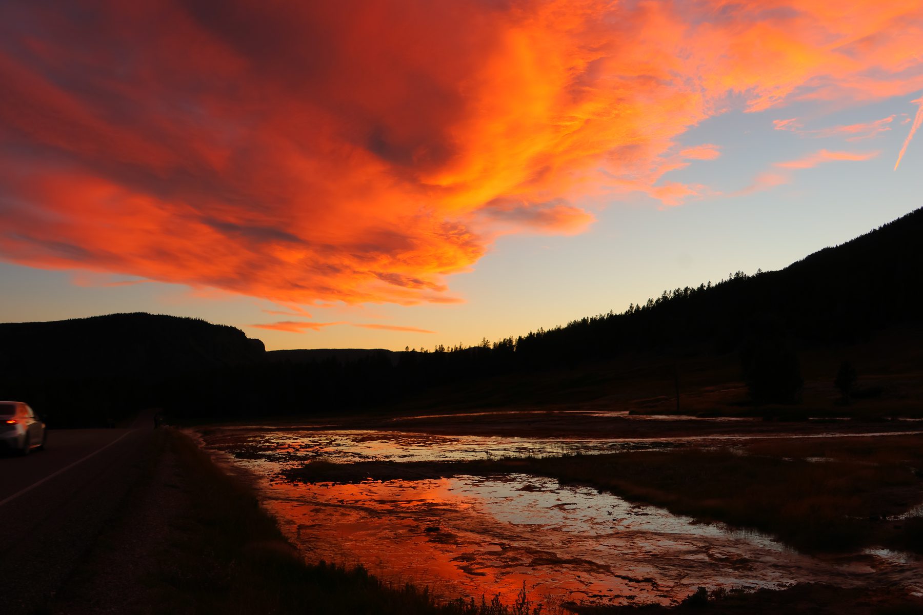 Scarlet sunset reflected in roadside water