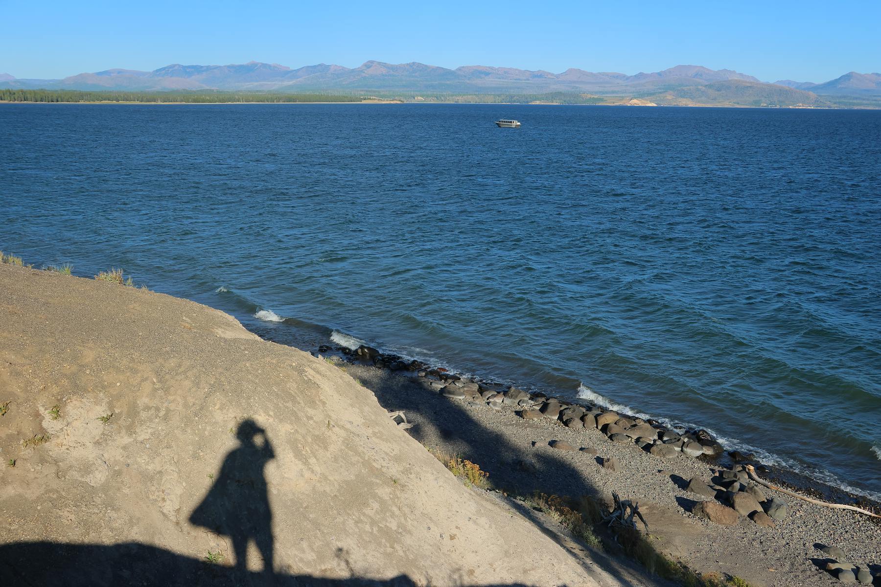 A photographer’s shadow on the shore of Yellowstone Lake